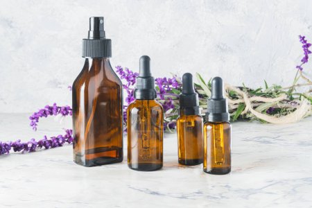 Photo for Bottles of different sizes of essential oils are a branch of lavender with flower with copy space - Royalty Free Image