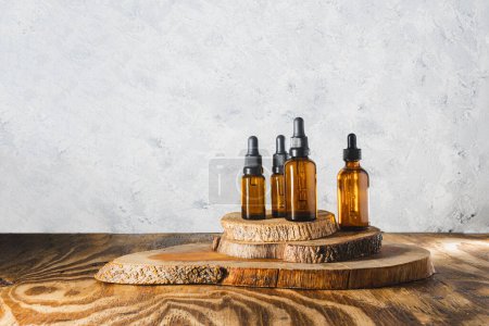 Photo for Still life of bottles of essential oils on driftwood on a gray textured background. Background with copy space - Royalty Free Image