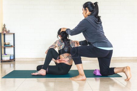 Téléchargez les photos : Professeur de yoga corriger la posture d'un étudiant faisant ardha matsyendrasana - en image libre de droit