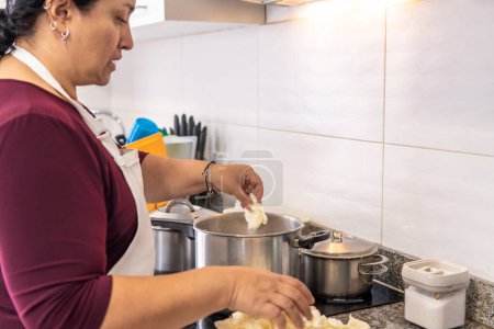 Téléchargez les photos : 50-year-old woman cooking in a pot on an induction stove. High quality photo - en image libre de droit