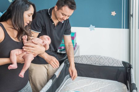 Téléchargez les photos : Les parents latins préparent leur bébé à aller à la crèche dans la chambre - en image libre de droit