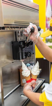 mains distribuant de la crème glacée d'une machine à crème glacée dans un centre commercial