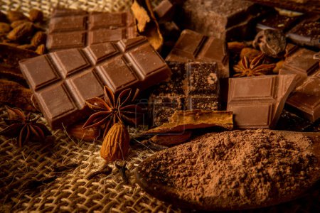 Stillleben mit Schokoladenstücken und Gewürzen wie Zimt, Sternanis und Mandeln auf Jutegrund