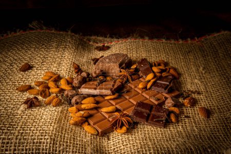 Photograph of pieces of chocolate with almonds on a rustic background on a sack