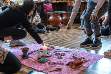Frauen legen für eine Willenszeremonie Gegenstände um eine Kerze auf eine Decke. Hochwertiges Foto