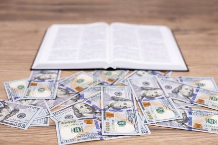 Un libro abierto de la Biblia sobre la mesa. Billetes de dólar. Elección: Riqueza o Dios. Es difícil para los ricos entrar en el Reino de Dios