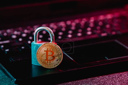 Foto de Bitcoin dorado y pequeño candado colocado en el teclado netbook como símbolos del comercio seguro de criptomonedas - Imagen libre de derechos