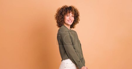 Smiled young curly haired female in makeup on beige background