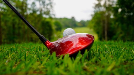 Golf ball and golf club in a beautiful golf course in Thailand. Collection of golf equipment resting on green grass with green background                      