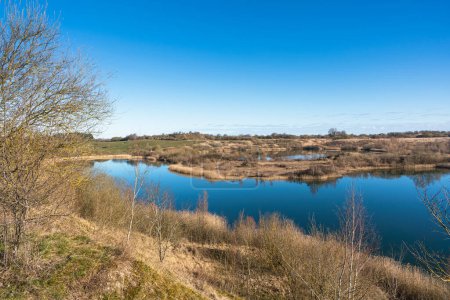 Vista sobre un paisaje con pequeñas colinas y lagos creados en un pozo de grava cerrado a principios de primavera Dinamarca