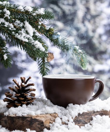 Téléchargez les photos : Boisson chaude à la vapeur dans une tasse de café sur un tronc d'arbre recouvert de neige avec un fond d'hiver - en image libre de droit