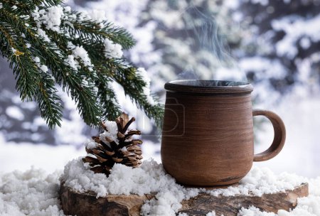 Photo for Steming hot drink in a coffee mug outdoors on a tree stump with a snowy winter background - Royalty Free Image
