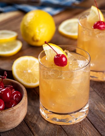 Photo for Whiskey sour cocktail with marachino cherry and lemon slice on rustic wooden table - Royalty Free Image