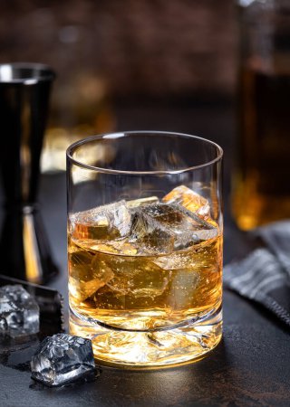 Foto de Glass of whiskey with ice drink on a dark wooden background - Imagen libre de derechos