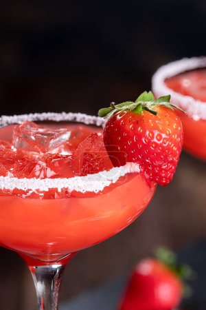 Photo for Strawberry margarita cocktail garnished with strawberrry and salt rim on a dark background.  Closeup with copy space - Royalty Free Image