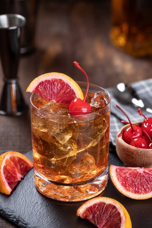Téléchargez les photos : Cocktail de whisky à l'ancienne avec des tranches de cerise et d'orange sur un fond de bois rustique - en image libre de droit
