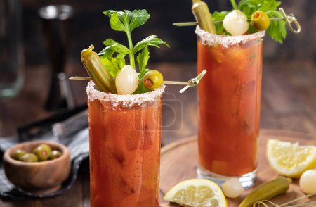 Téléchargez les photos : Cocktail de Marie sanglante garni de céleri, gombo, oignon, olive et sel sur fond de bois foncé - en image libre de droit