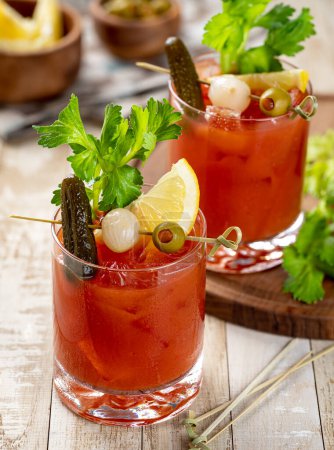 Téléchargez les photos : Cocktail de Marie sanglante garni de céleri, citron, cornichon, oignon et olive sur une table en bois - en image libre de droit