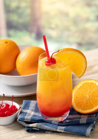 Photo for Tequila sunrise cocktail with orange slice and cherry on wooden table with summer background and copy space - Royalty Free Image