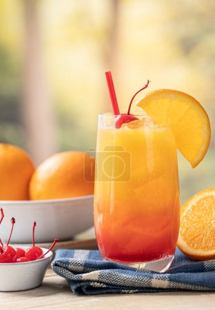 Téléchargez les photos : Cocktail lever de soleil à la tequila avec tranche d'orange et cerise sur table en bois avec fond d'été et espace de copie - en image libre de droit