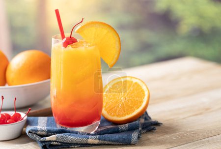 Photo for Tequila sunrise cocktail with orange slice and cherry on wooden table with summer backgroundand copy space - Royalty Free Image