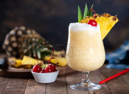 Photo for Pina colada cocktail with cherry, pineapple slice and leaves on a dark background with copy space - Royalty Free Image