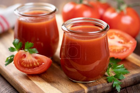 Téléchargez les photos : Jus de tomate dans des bocaux en verre avec des tranches fraîches et des tomates sur un plateau en bois - en image libre de droit