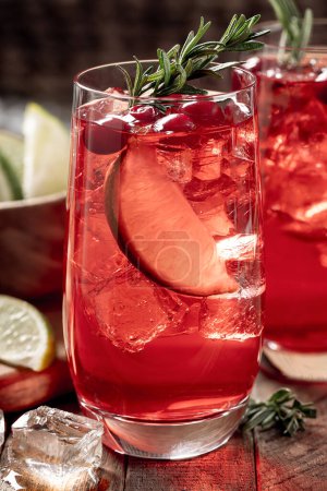 Photo for Cranberry with lime slices and garnished with rosemary on rustic wooden table - Royalty Free Image