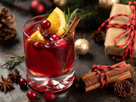 Photo for Mulled red wine with cranberries, orange slices, cinnamon, rosemary and anise.  Christmas holiday decorations in background - Royalty Free Image
