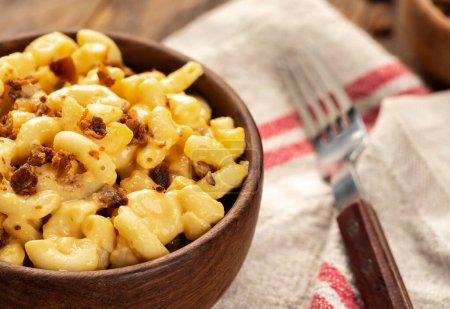 Téléchargez les photos : Gros plan de macaronis et fromage avec des morceaux de bacon dans un bol en bois sur une serviette - en image libre de droit