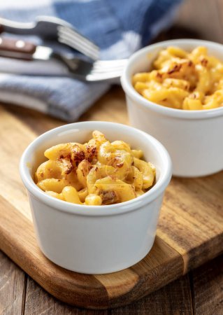 Téléchargez les photos : Macaronis au four et fromage dans une tasse blanche sur une planche de bois - en image libre de droit