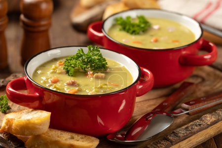 Téléchargez les photos : Deux bols de soupe aux pois cassés au jambon et aux carottes garnis de persil sur un plateau rustique en bois - en image libre de droit