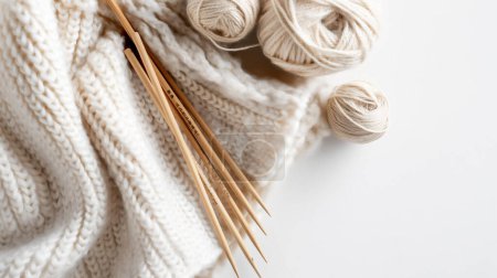 Echarpe tricotée à la crème avec aiguilles à tricoter en bambou et boules de laine.