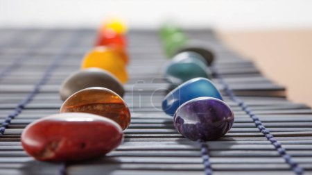 Colorful stones arranged in a row on a textured mat, varying in hues and sizes.