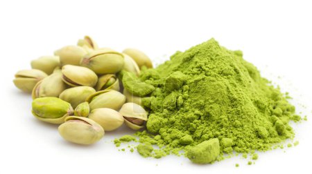 Pistachio nuts beside a mound of vibrant green pistachio powder on a white background.