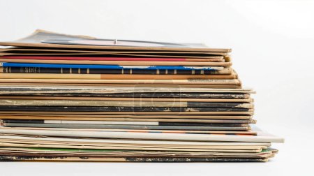 Empilement de vieilles couvertures de disques usées, évoquant la nostalgie et le passage du temps.
