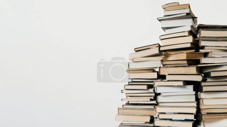 A tall stack of various hardcover and paperback books against a white background.