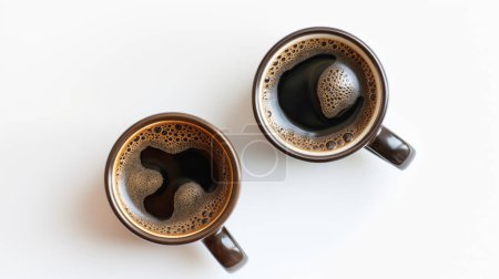 Two cups of coffee with froth, seen from above on a white background.