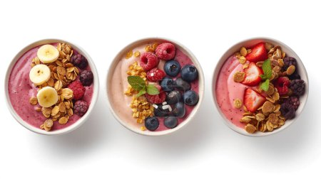 Three bowls of smoothie topped with various fruits and granola on white background.