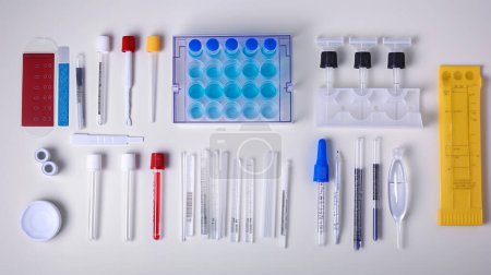 Assorted laboratory equipment neatly arranged on a white surface, including tubes and pipettes.