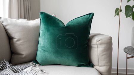 Emerald green velvet pillow on a beige couch, interior design details.