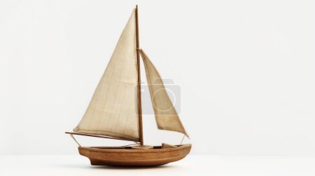 A minimalist wooden model sailboat with beige sails, standing against a plain white background, representing classic nautical charm.
