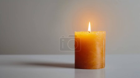 A single lit candle with a soft orange glow, casting a warm light on a plain background, creates a peaceful ambiance.