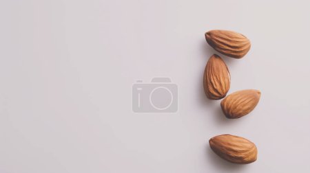 Four whole almonds arranged vertically on a light beige background.