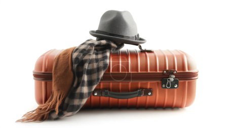 Orange suitcase with a gray fedora hat and a plaid scarf draped over it, suggesting travel and style.