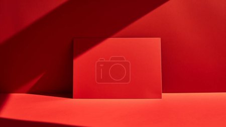 Un objeto rectangular rojo se coloca sobre un fondo rojo con sombras nítidas creando una composición minimalista y monocromática.