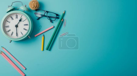 A pastel-colored alarm clock surrounded by pencils, paper clips, glasses, and a ball of twine on a blue background, evoking a sense of organization and study.