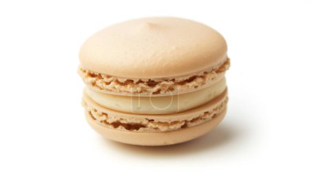 Un único macaron beige con un relleno cremoso, con una parte superior lisa y un borde texturizado, sobre un fondo blanco.