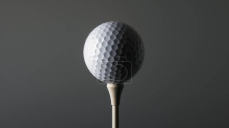 Primer plano de una pelota de golf sobre un tee sobre un fondo oscuro, destacando sus hoyuelos y textura superficial.