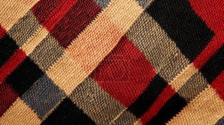 Primer plano de un tejido de punto con un patrón a cuadros rojo, negro y beige, mostrando textura y artesanía.